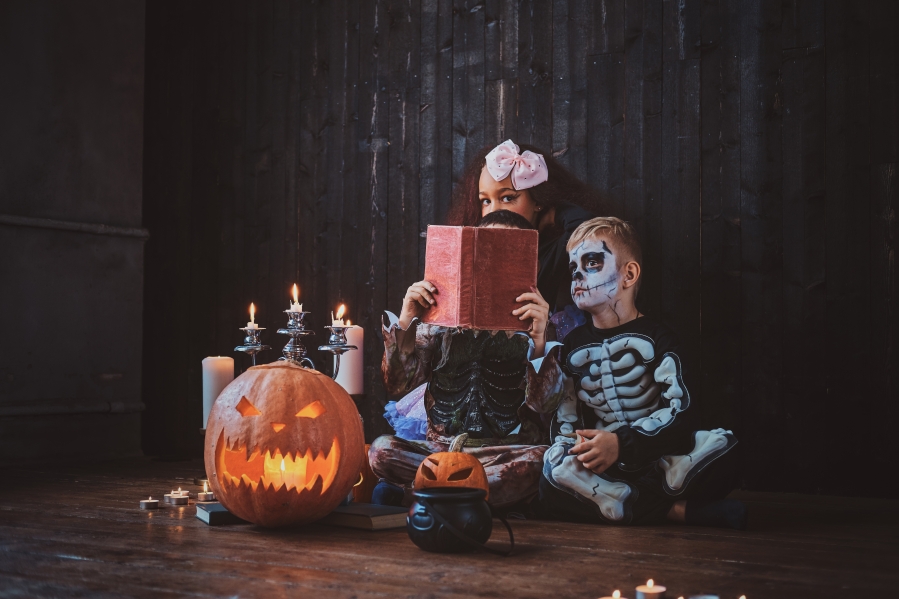 pretty-little-kids-in-halloween-costumes-are-enjoying-party-while-reading-book
